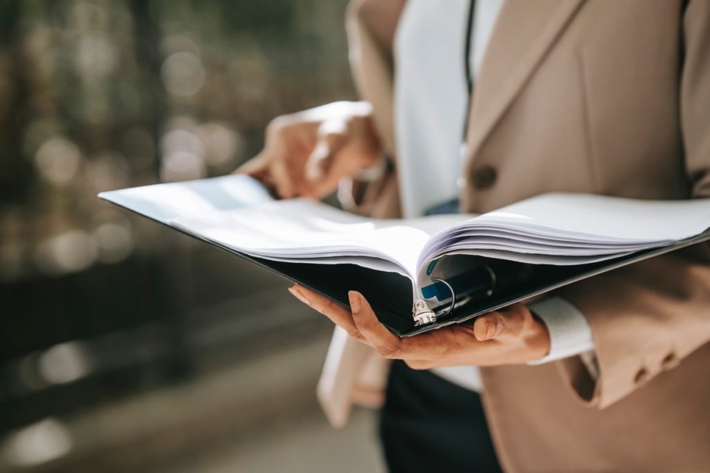 Une femme tient un classeur de rapports d'interventions imprimés sur papier